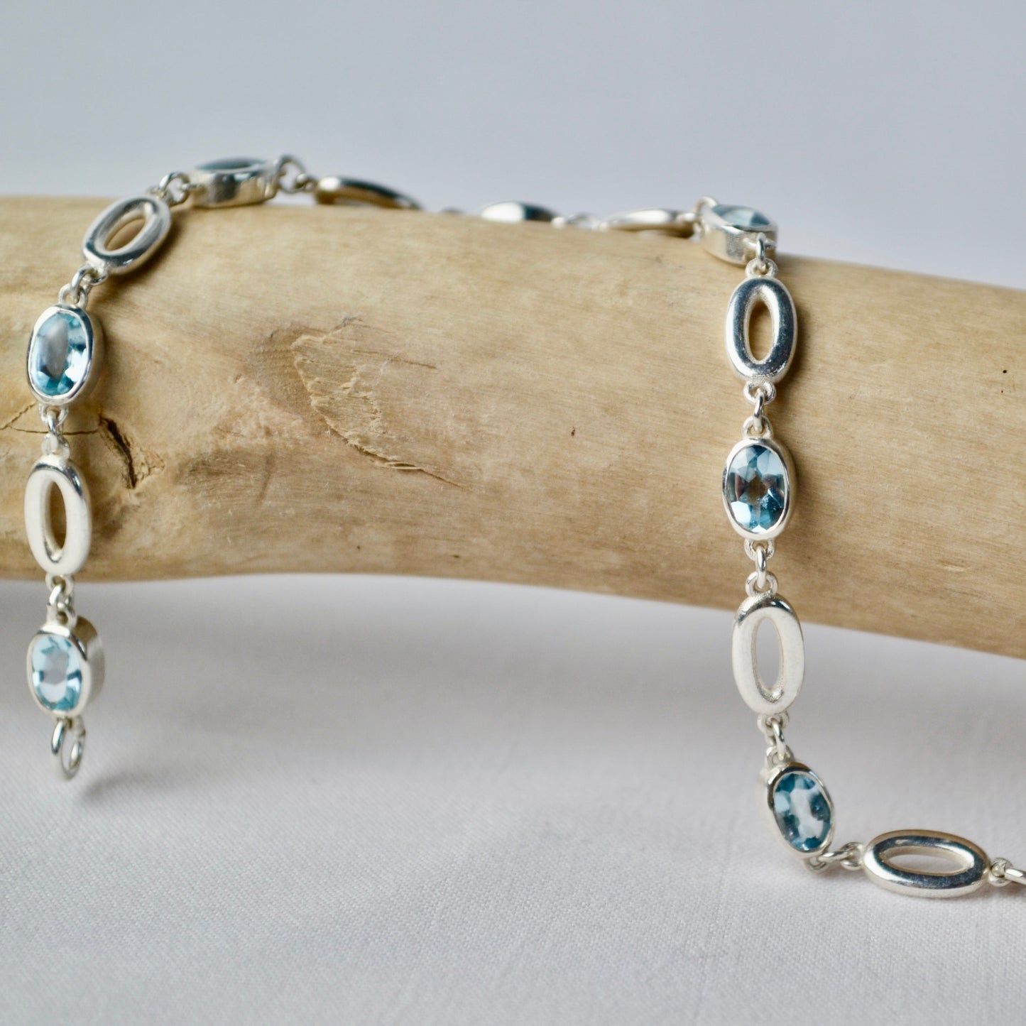 Silver bracelet with blue gemstones on a wooden branch