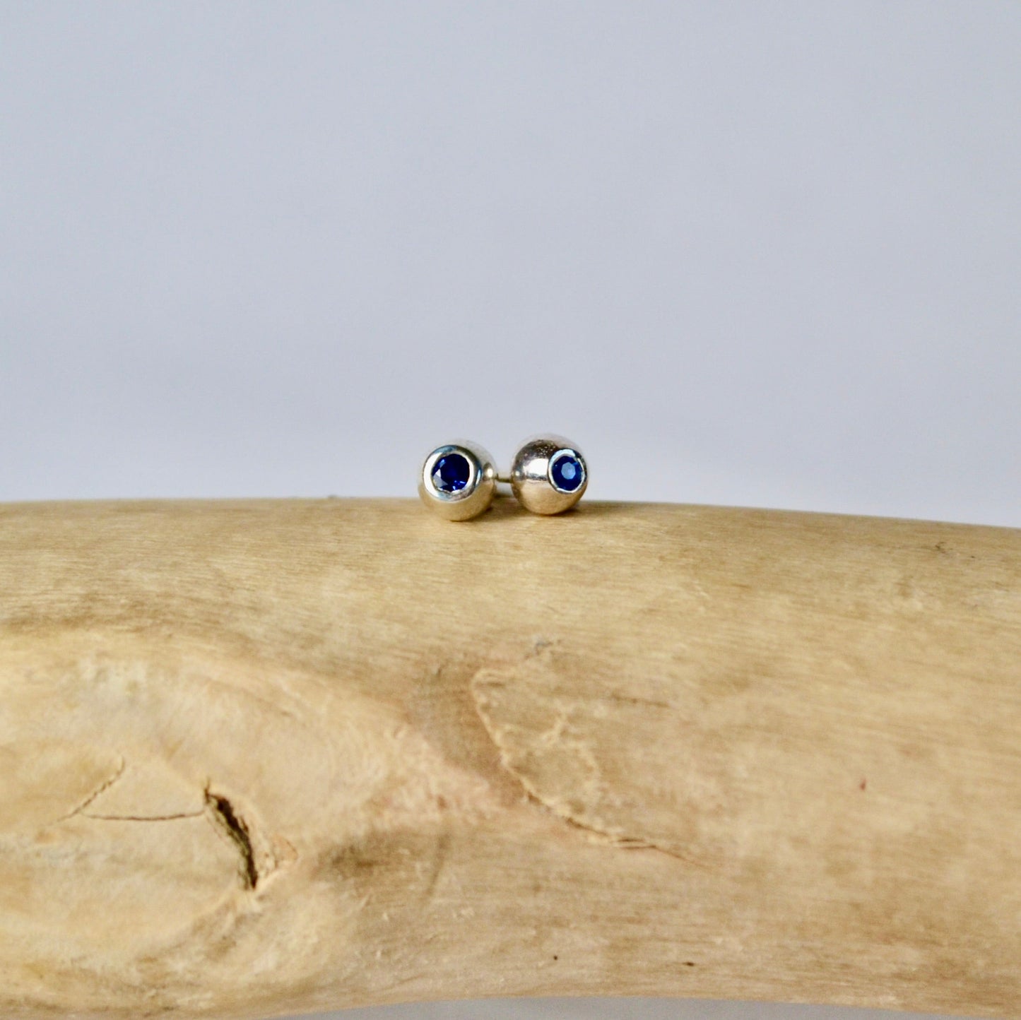 Gold earrings with blue stones on a wooden surface