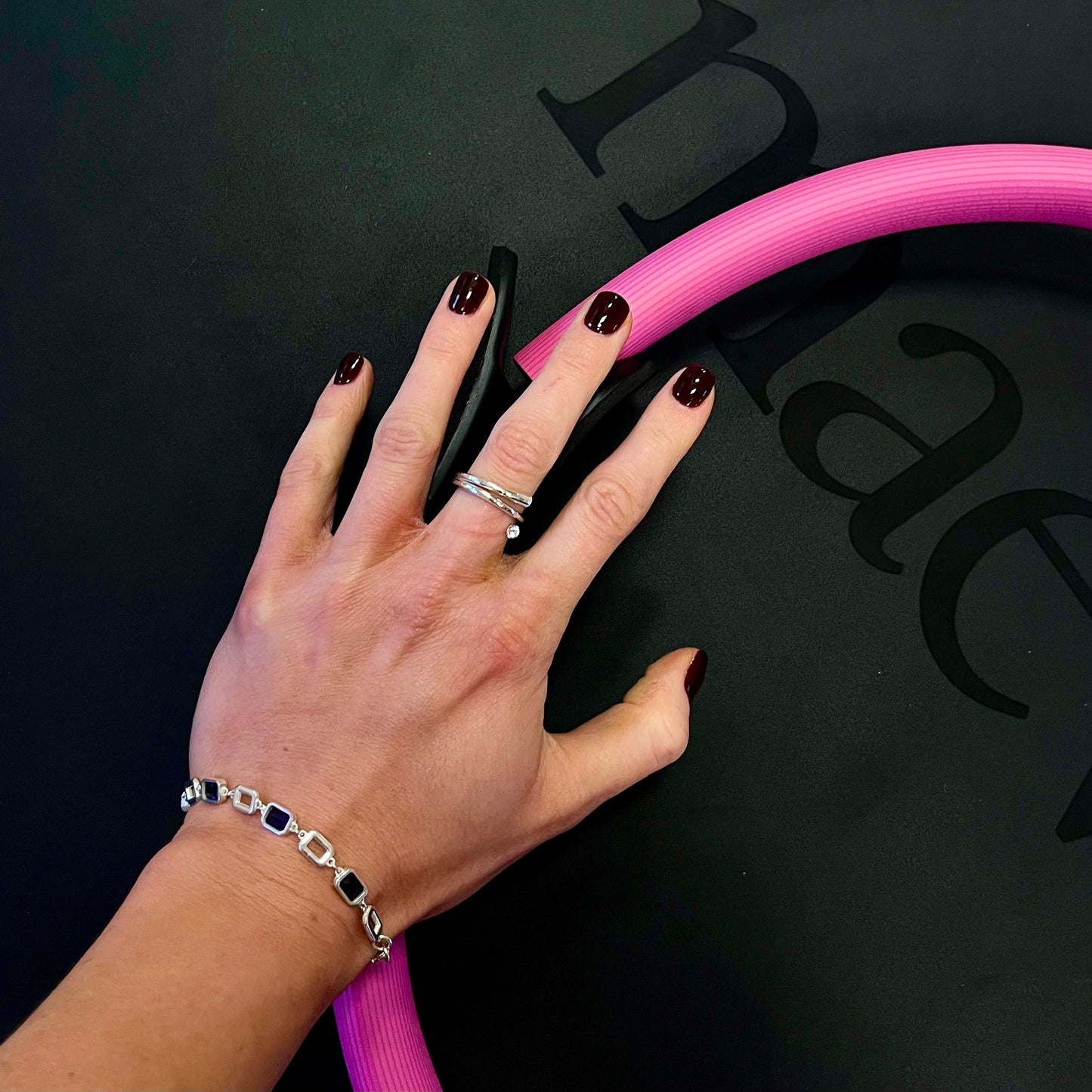 Hand with a pink tube against a black background with visible branding