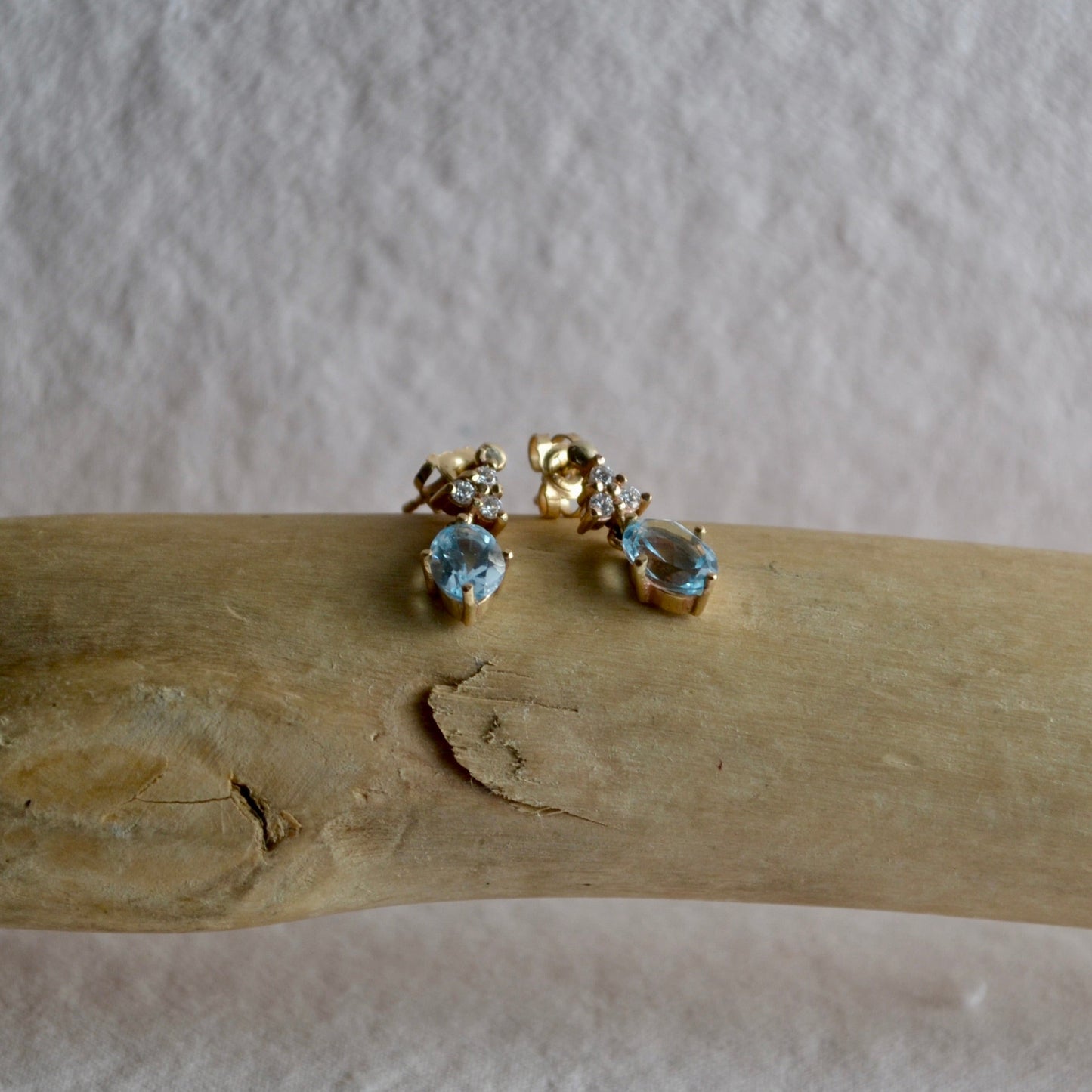 Gold earrings with gemstones on a wooden surface