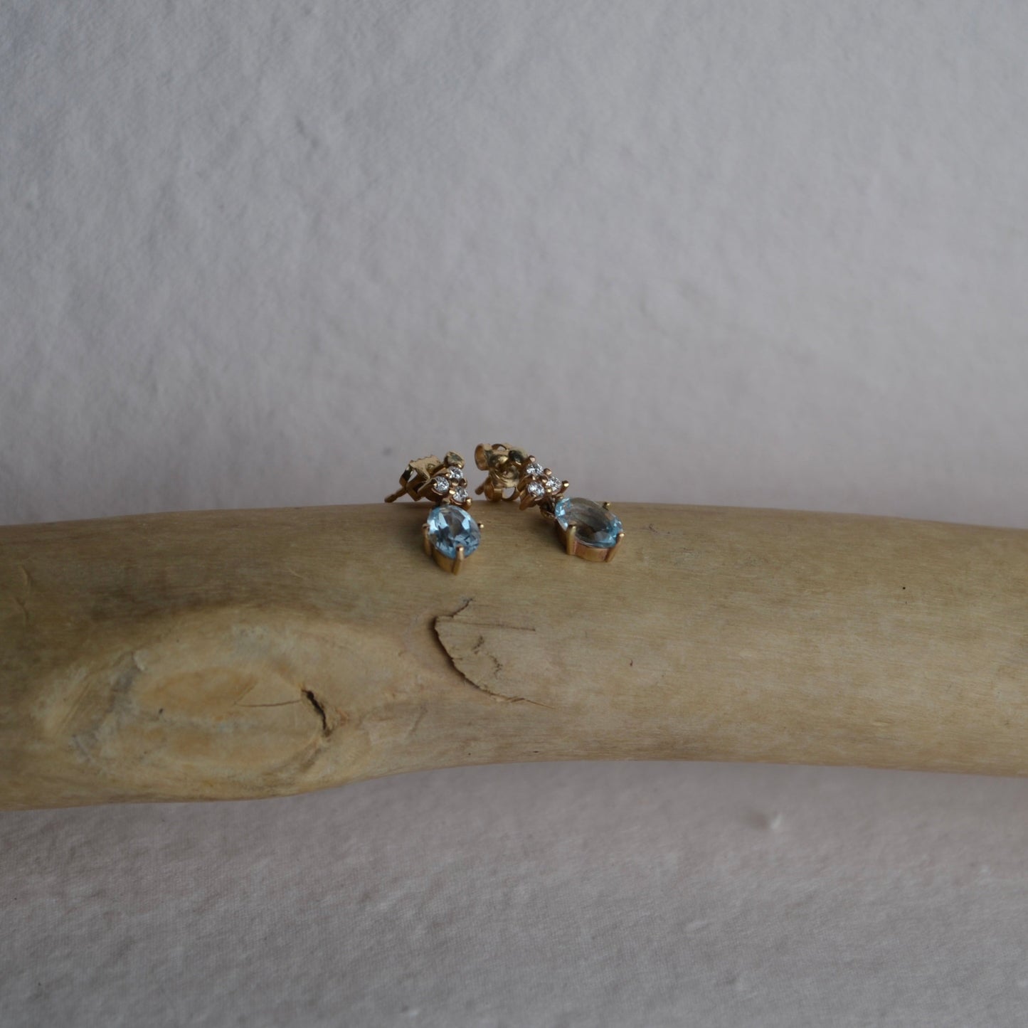 Pair of earrings on a wooden stick against a plain background