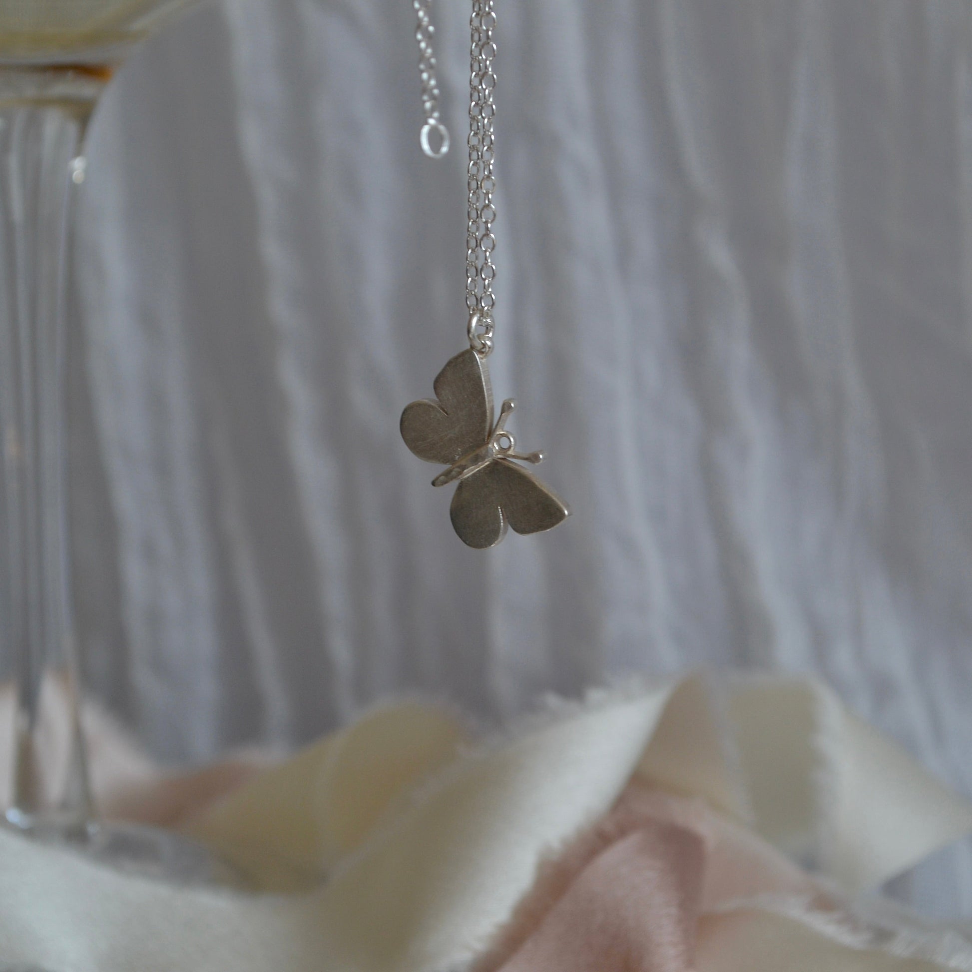 Butterfly pendant necklace on a blurred background