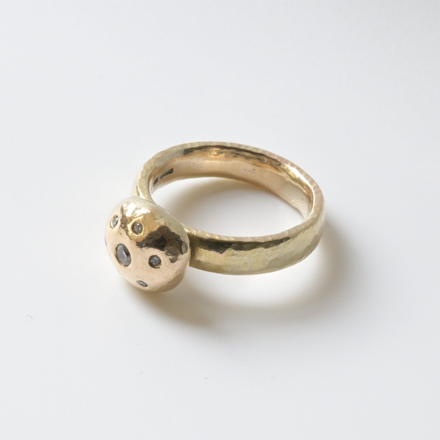 A 9ct yellow gold ring with a floral pattern of set white diamonds on a rustic gold band.