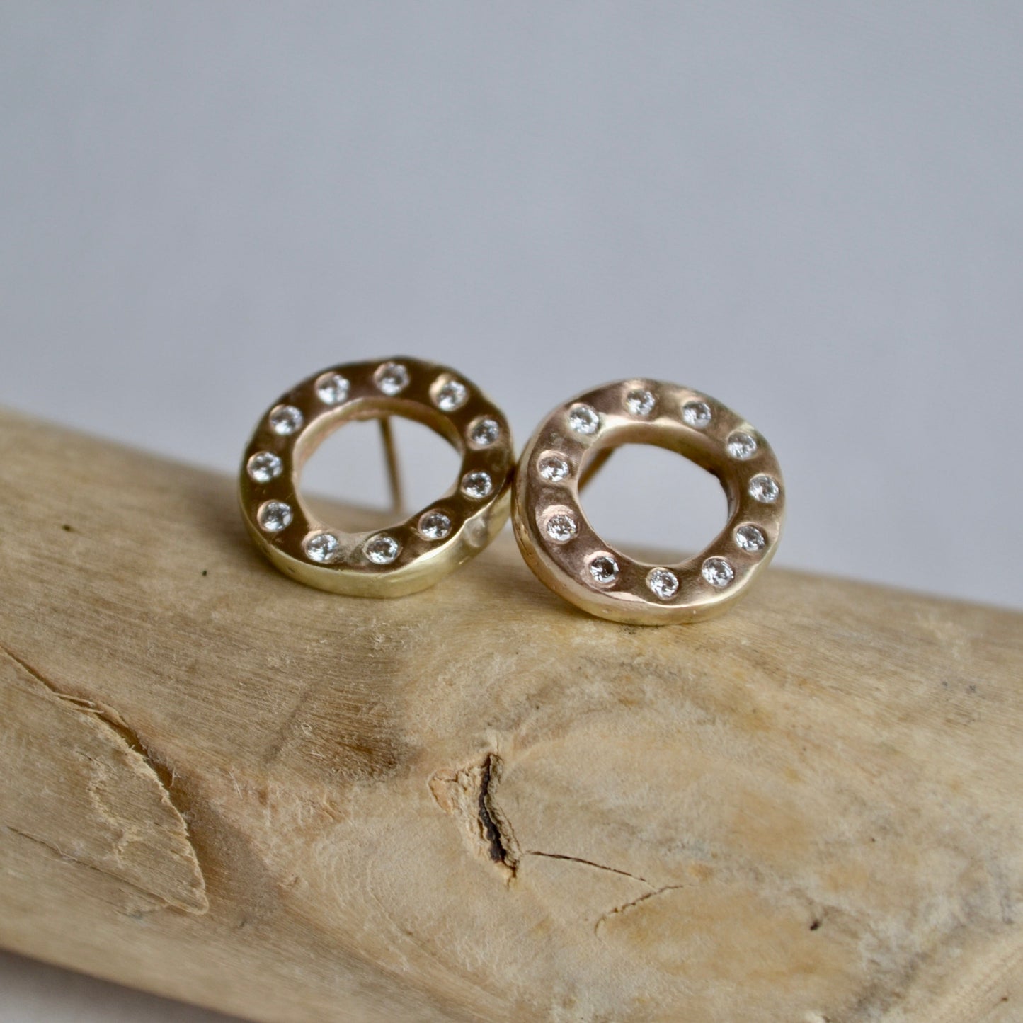 Gold earrings with small diamonds on a wooden surface