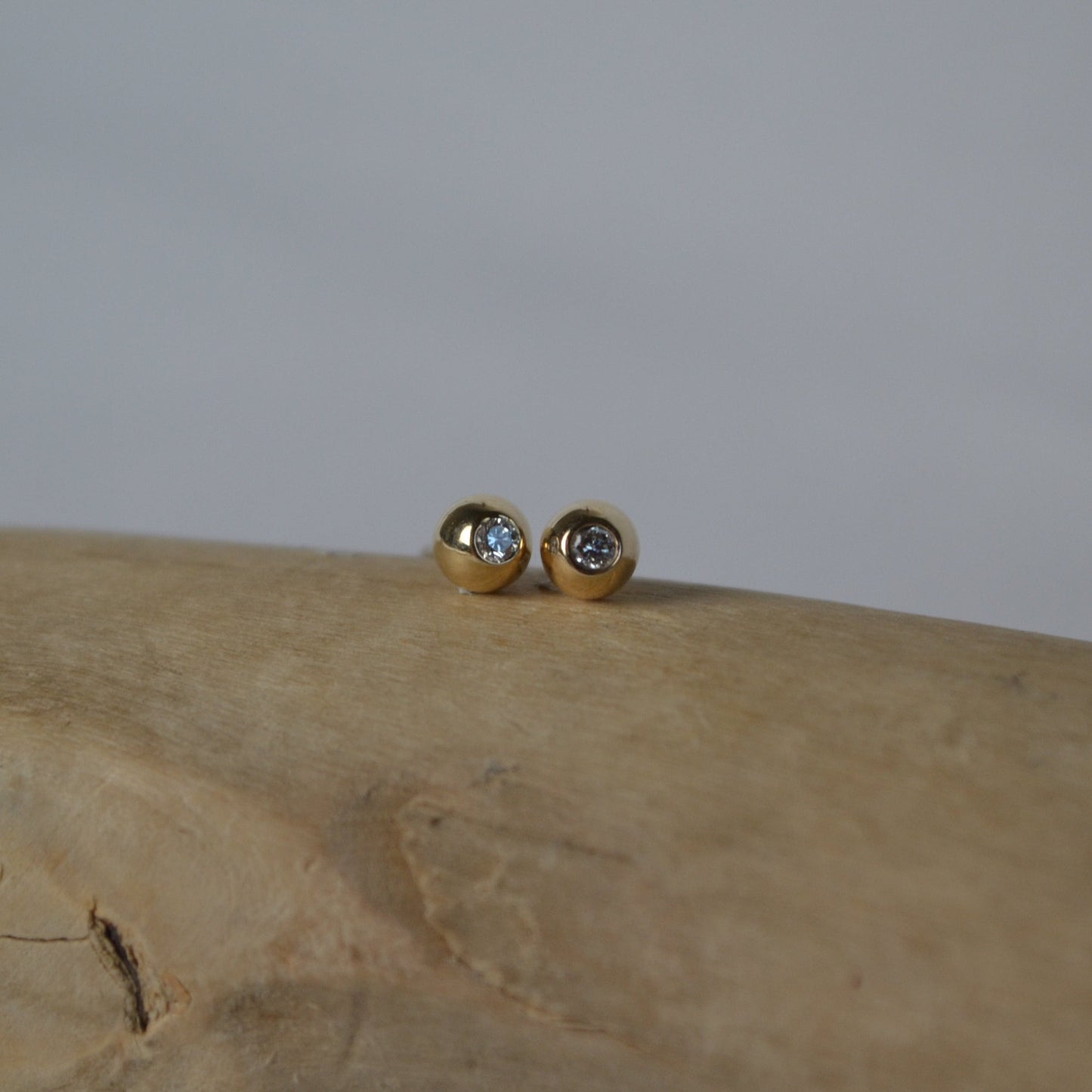 Gold earrings with gemstones on a wooden surface