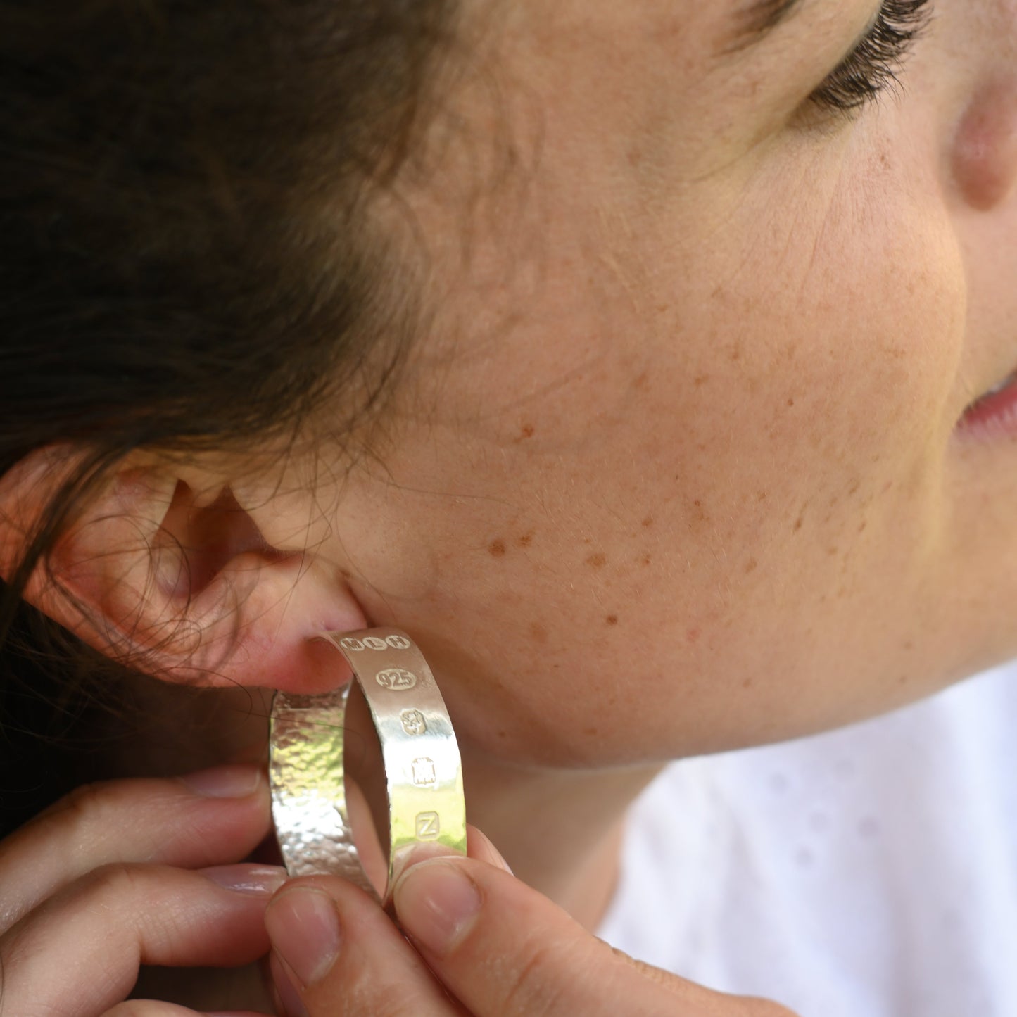 madeleine putting on hallmarked silver hoops in the garden.