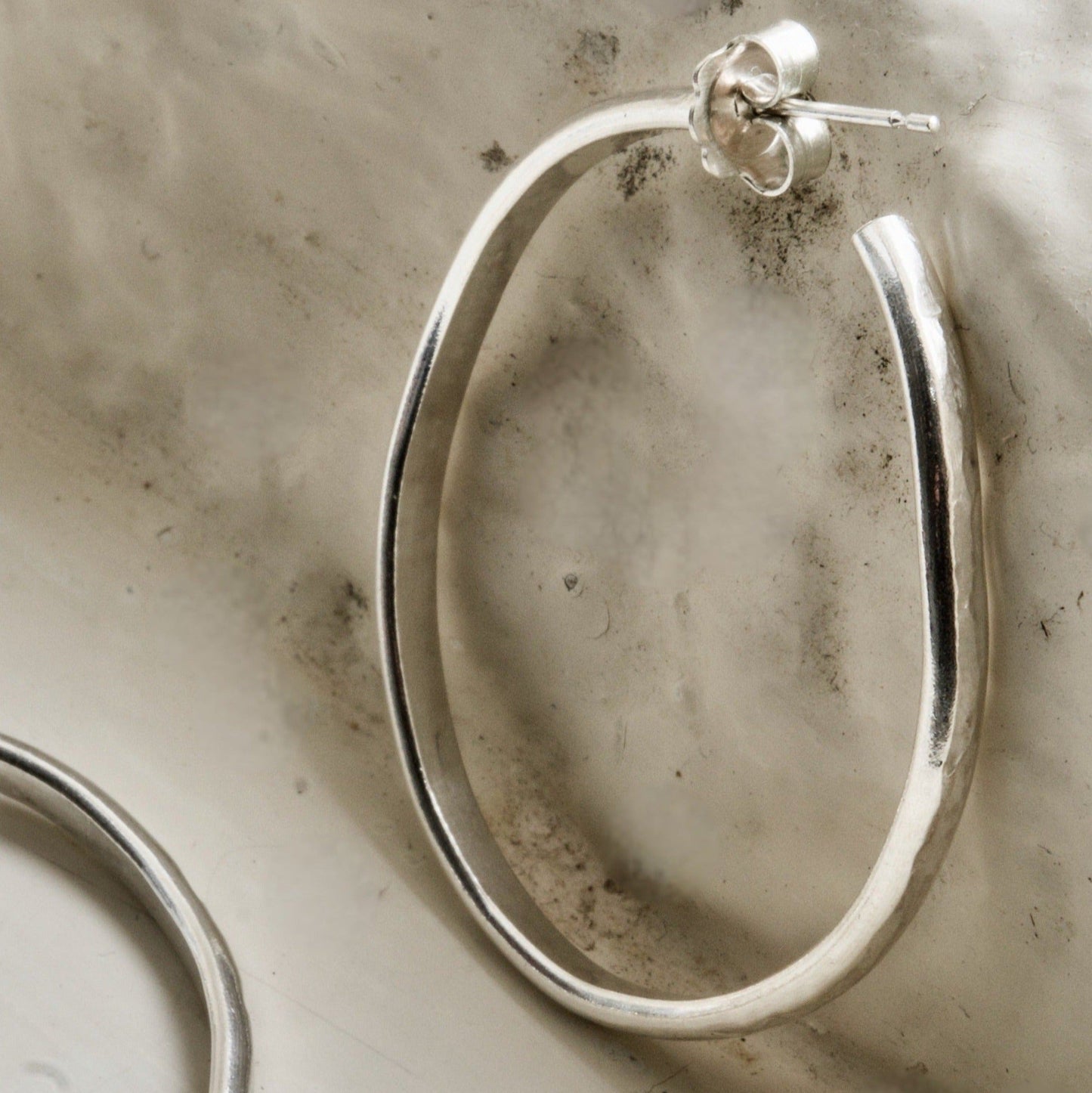 Classic silver hoop photographed on a rustic white Cotswold stone background.