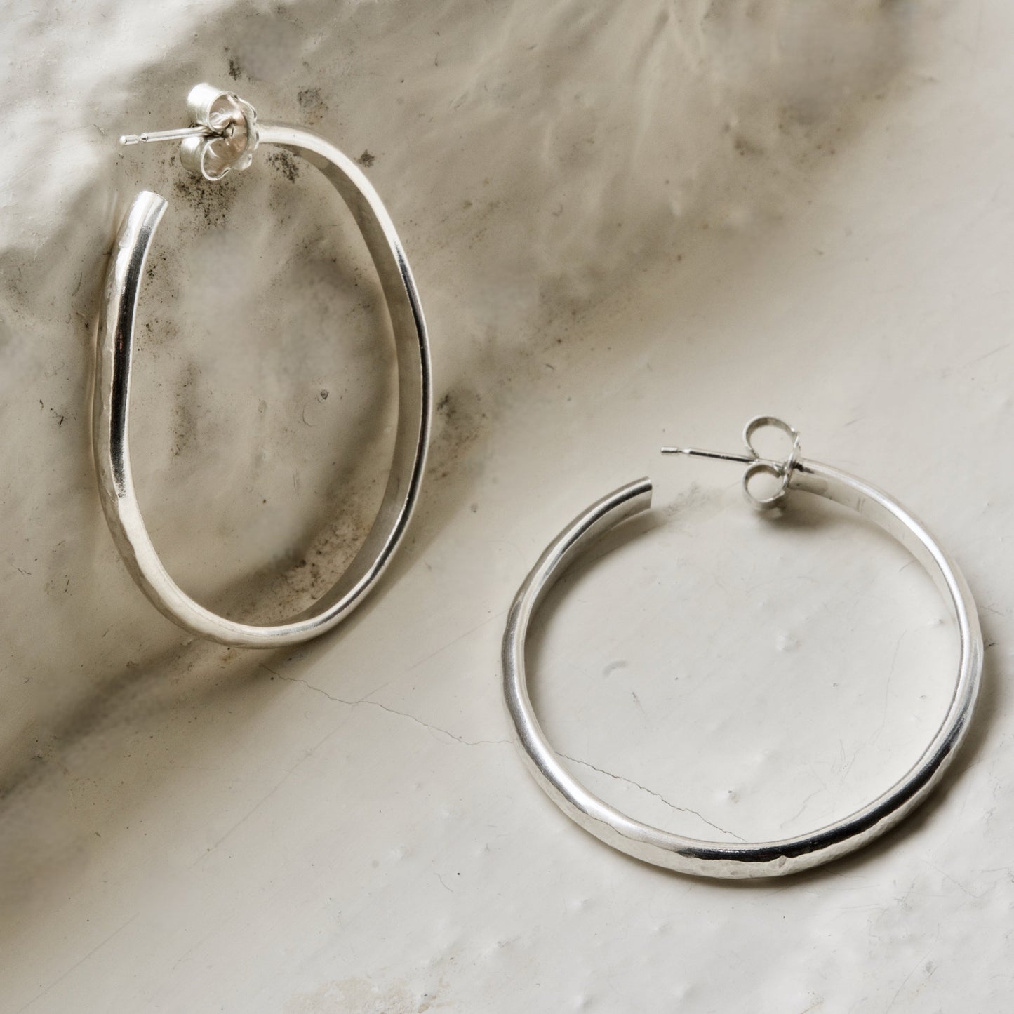 Classic pair of sterling silver hoops, photographed on white brick in the Cotswolds.