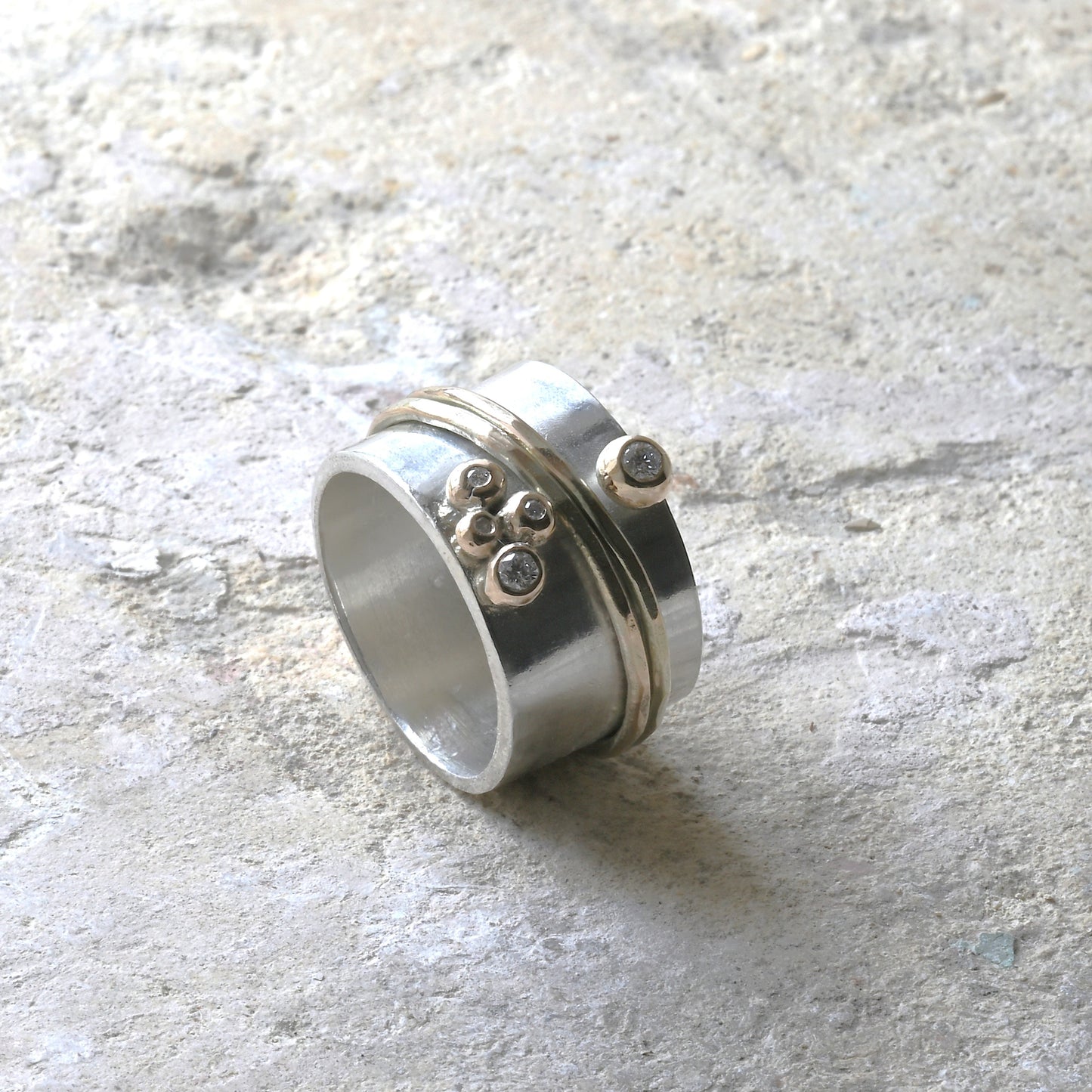 gold, diamond and silver spinning ring photographed on Cotswold stone. Handmade fine jewellery by Madeleine.
