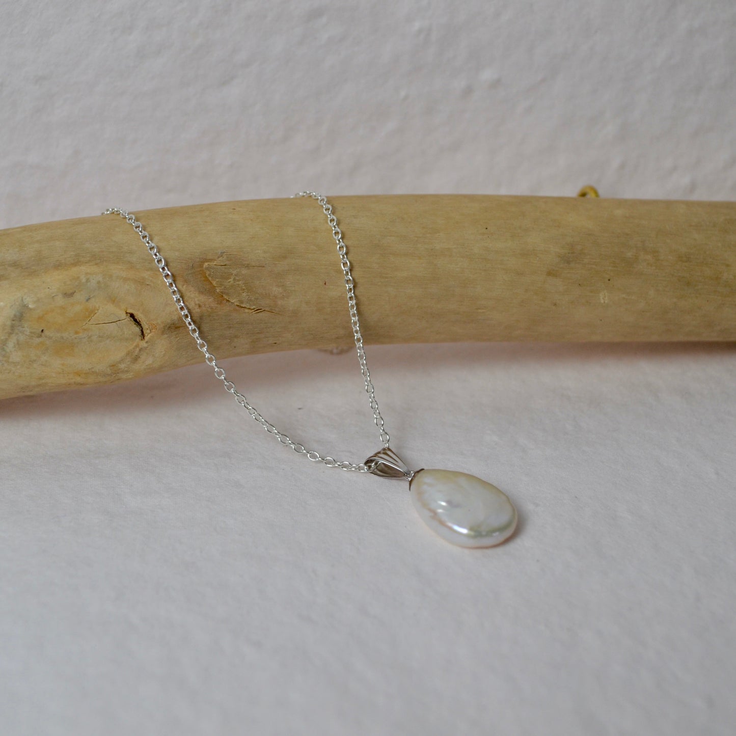Necklace with a pendant on a wooden stick against a light background