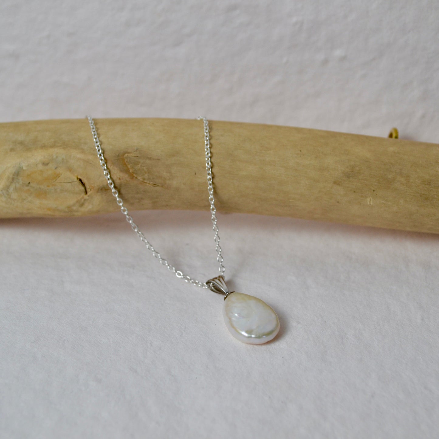 Silver necklace with a teardrop-shaped pendant on a white background