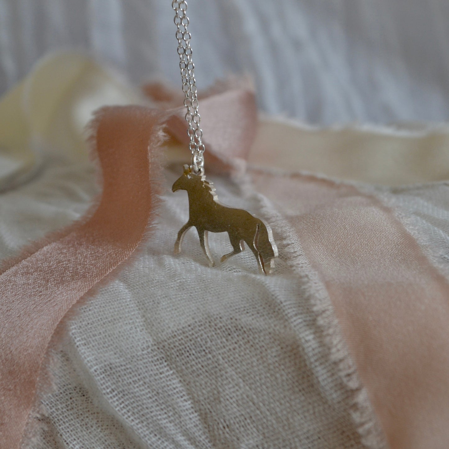 Necklace with a horse pendant on a soft fabric background