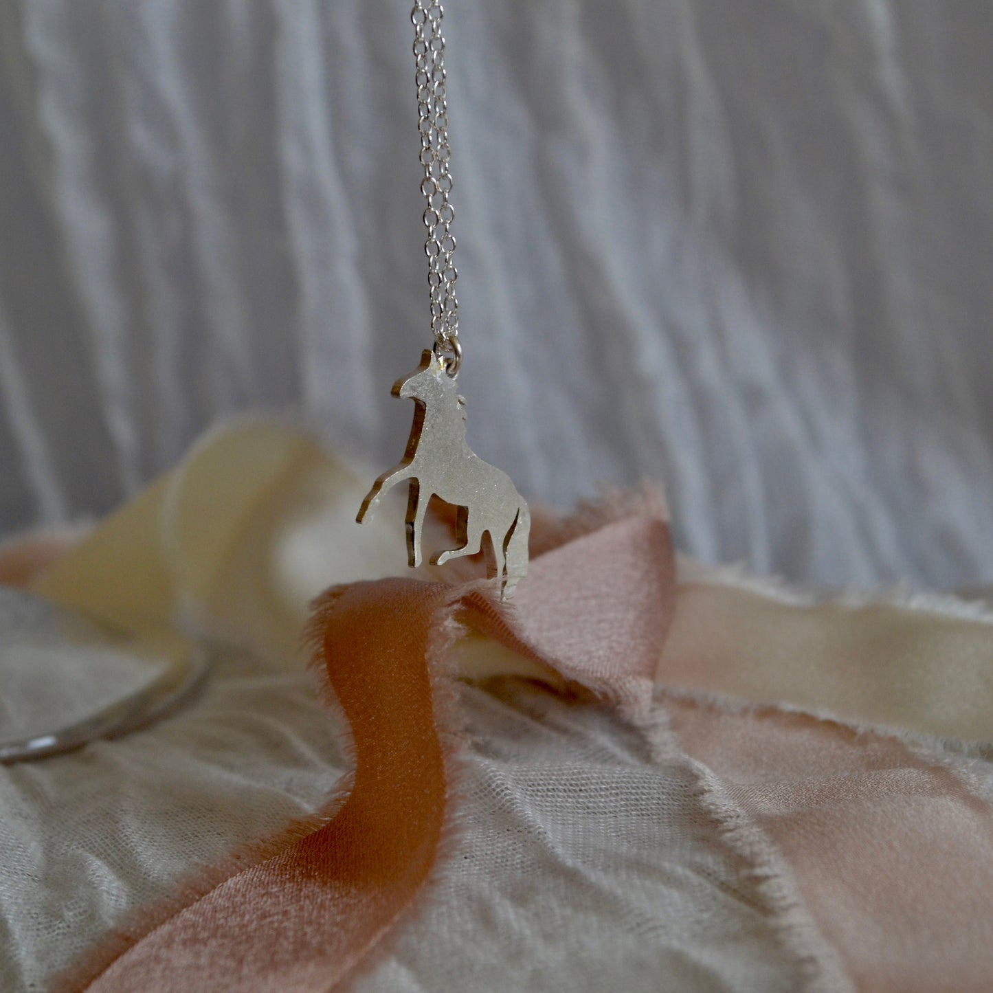 Necklace with a horse pendant on a textured surface