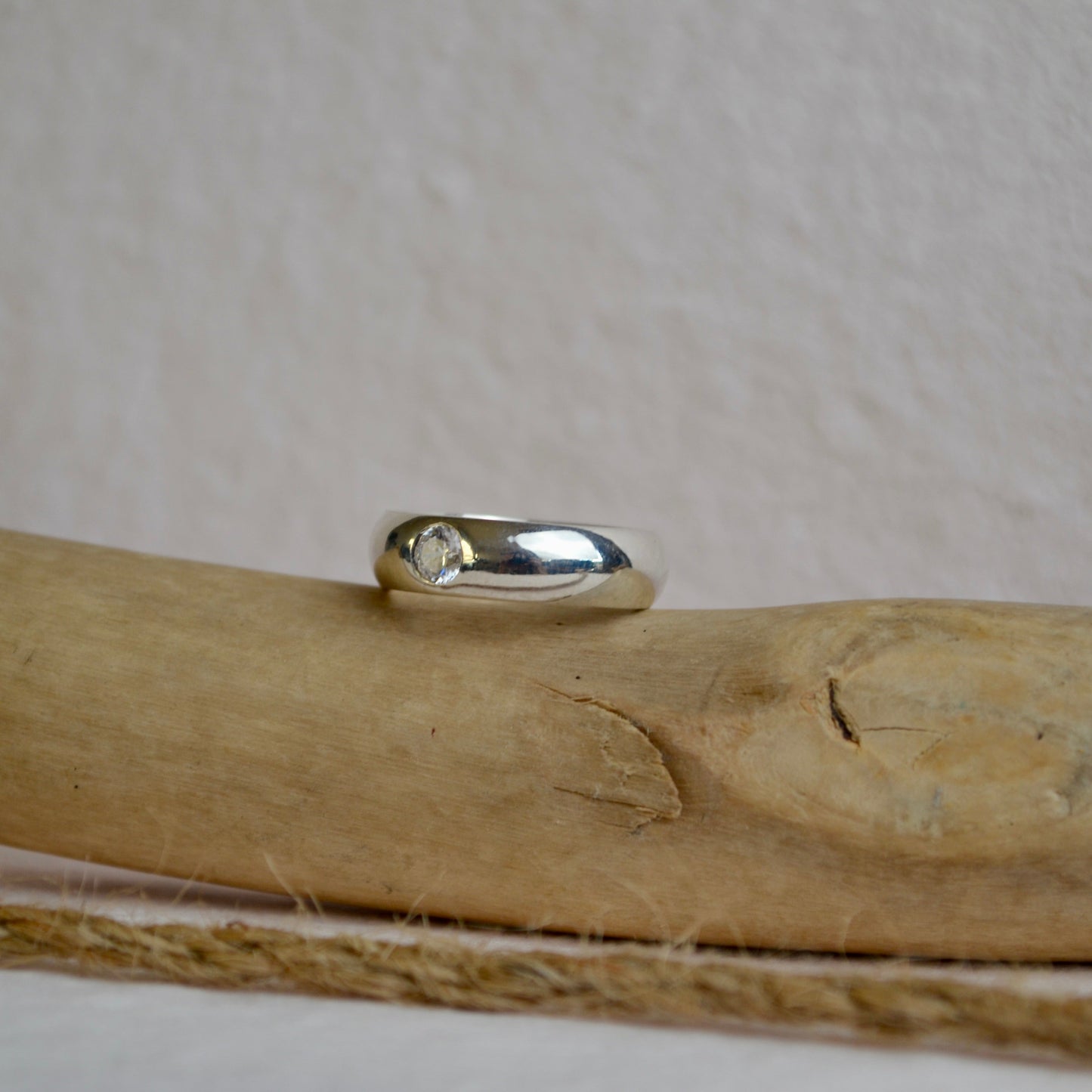 Silver ring on a wooden surface with a beige background