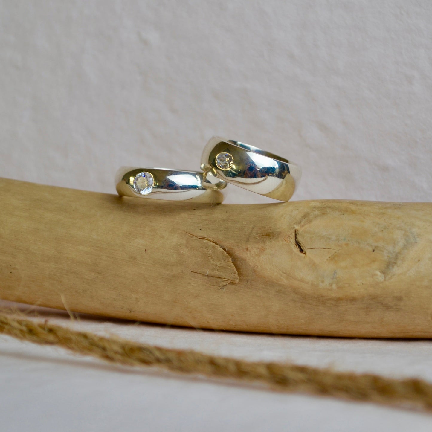 Silver ring with small stones on a wooden stick against a white background