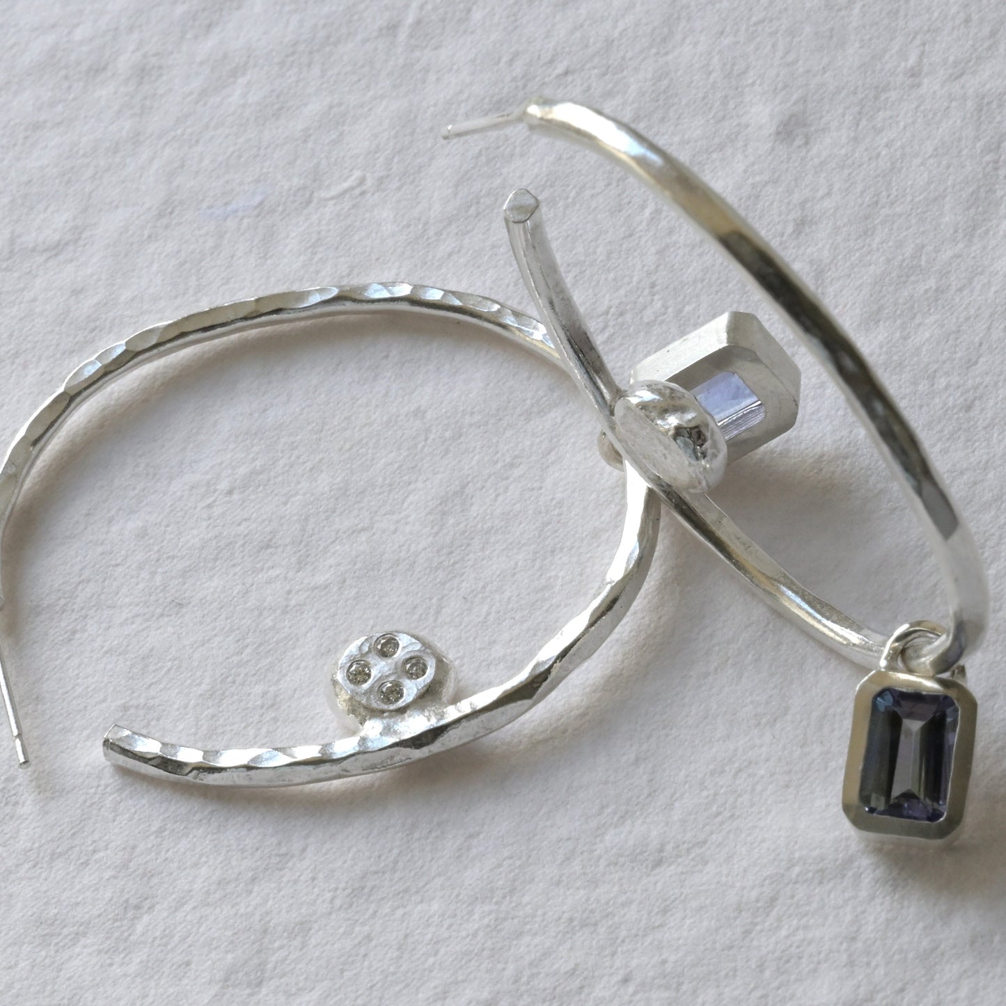 Sterling silver diamond and tanzanite sterling silver hoops photographed on white. Handmade fine jewellery by Madeleine.