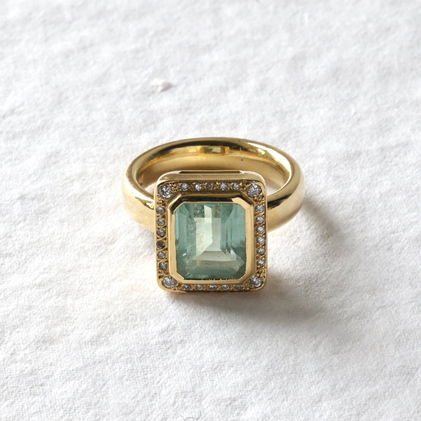Gold ring with a green gemstone on a white background