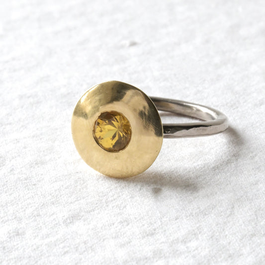 An 18ct gold engagement ring with a yellow sapphire at its centre, displayed on a white background.