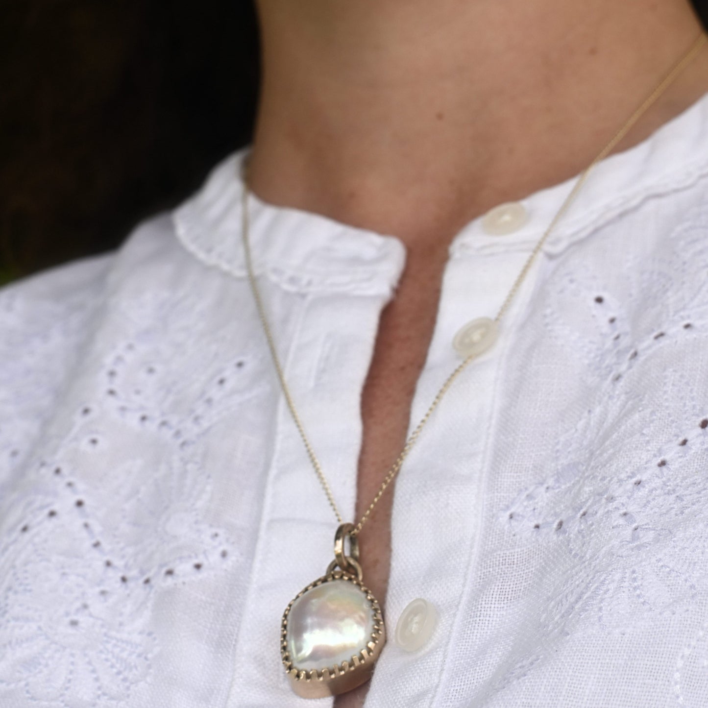 Madeleine in white shirt wearing wedding day pearl earrings and necklace.