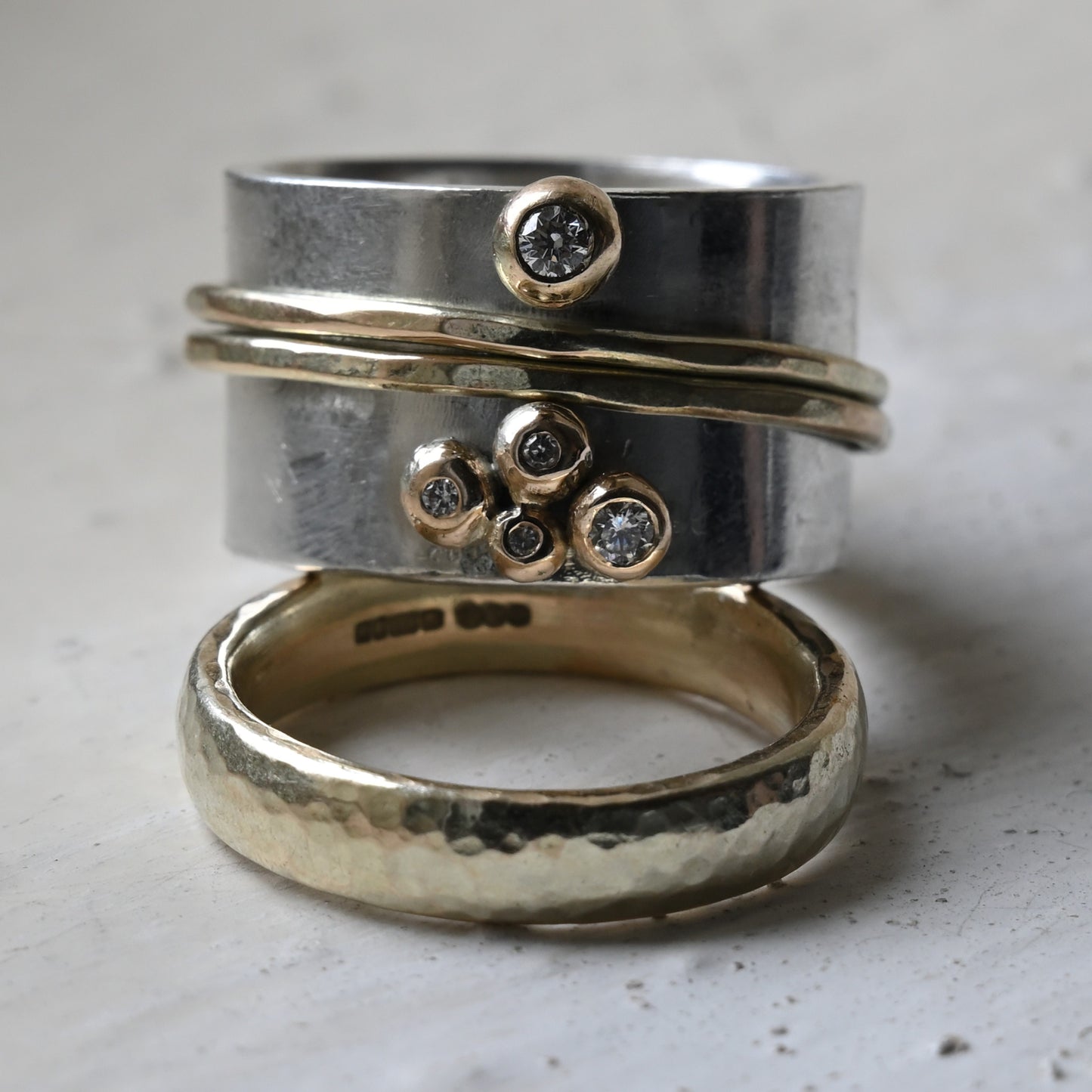 silver and gold diamond spinning ring stacked on a gold wedding band. Handmade fine jewellery by Madeleine.