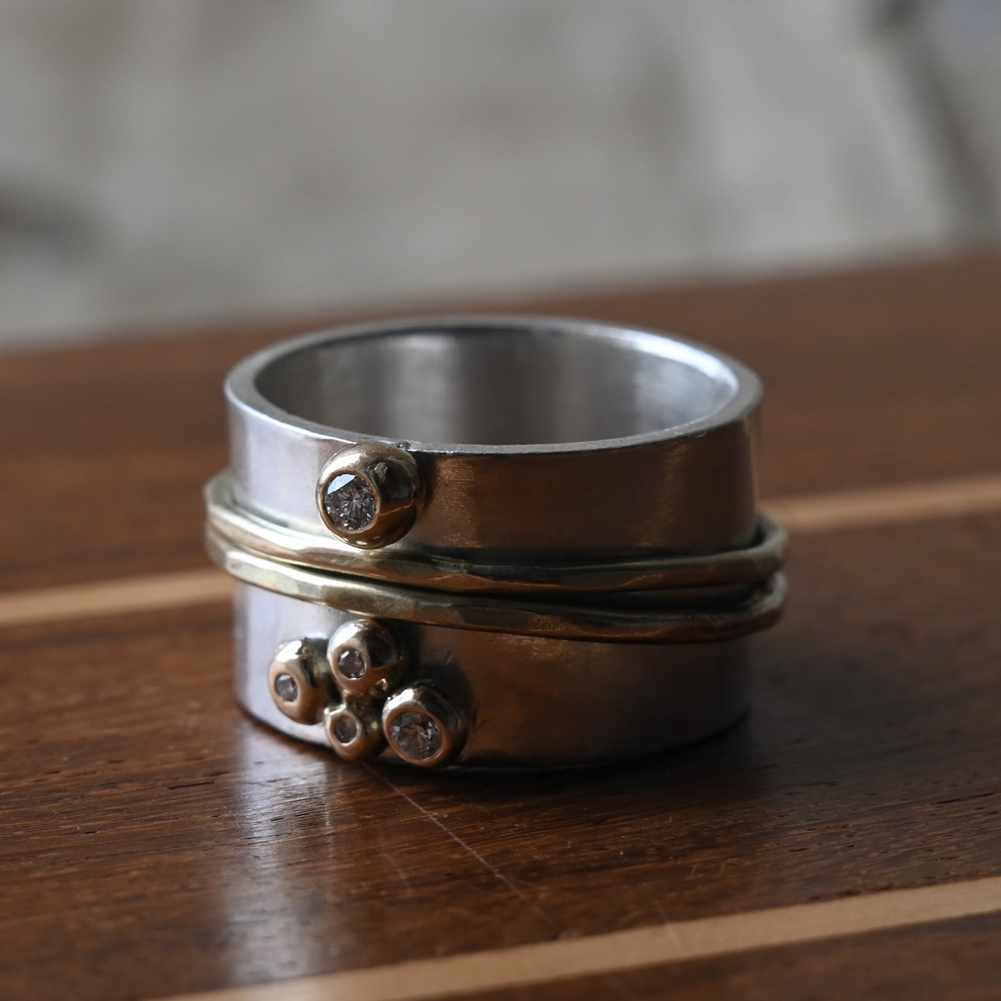 gold, silver and diamond spinning ring. Photographed on traditional wood. Handmade fine Jewellery by Madeleine.