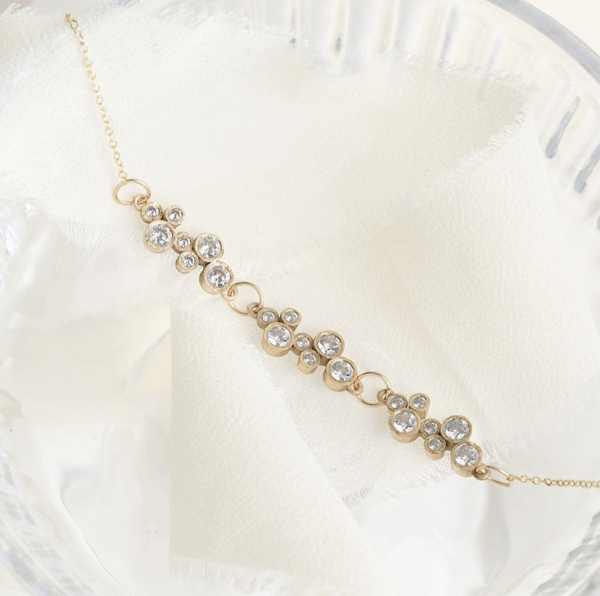 Delicate gold bracelet with small pearls on a white marble surface