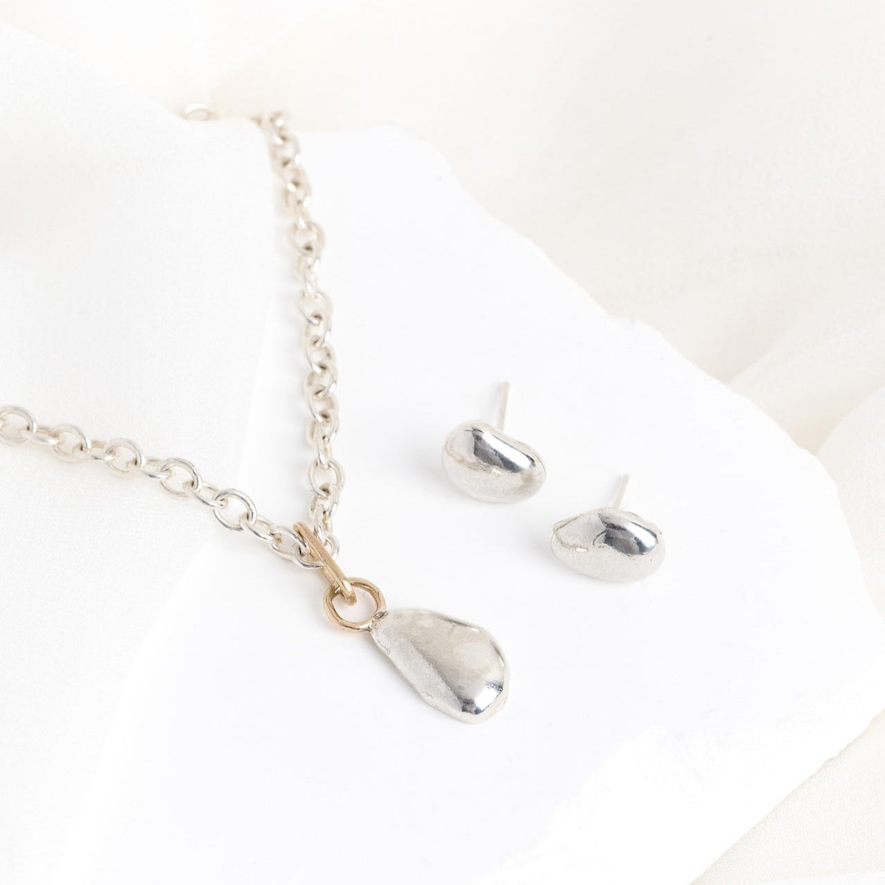 Silver necklace with teardrop pendants on a white background