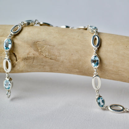 Silver bracelet with blue gemstones on a wooden branch