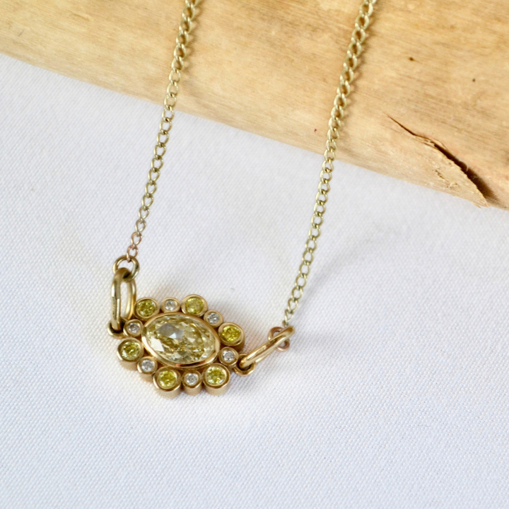 Gold necklace with a pendant featuring a yellow gemstone on a white background