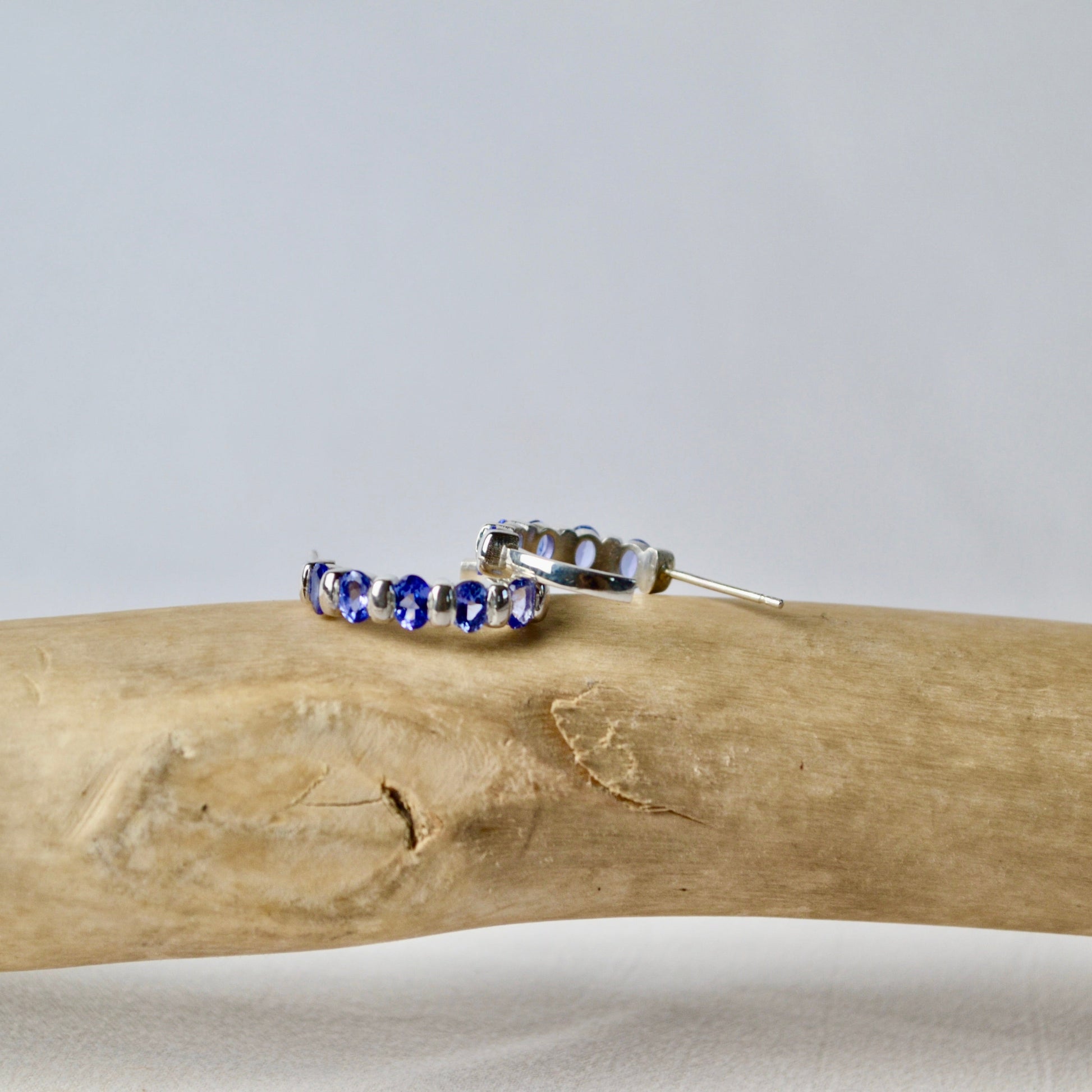 Silver ring with blue stones on a piece of driftwood against a light gray background