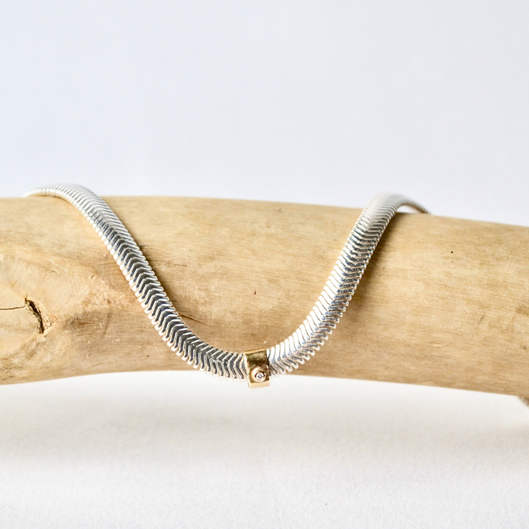 Necklace with a gold clasp on a wooden branch against a white background