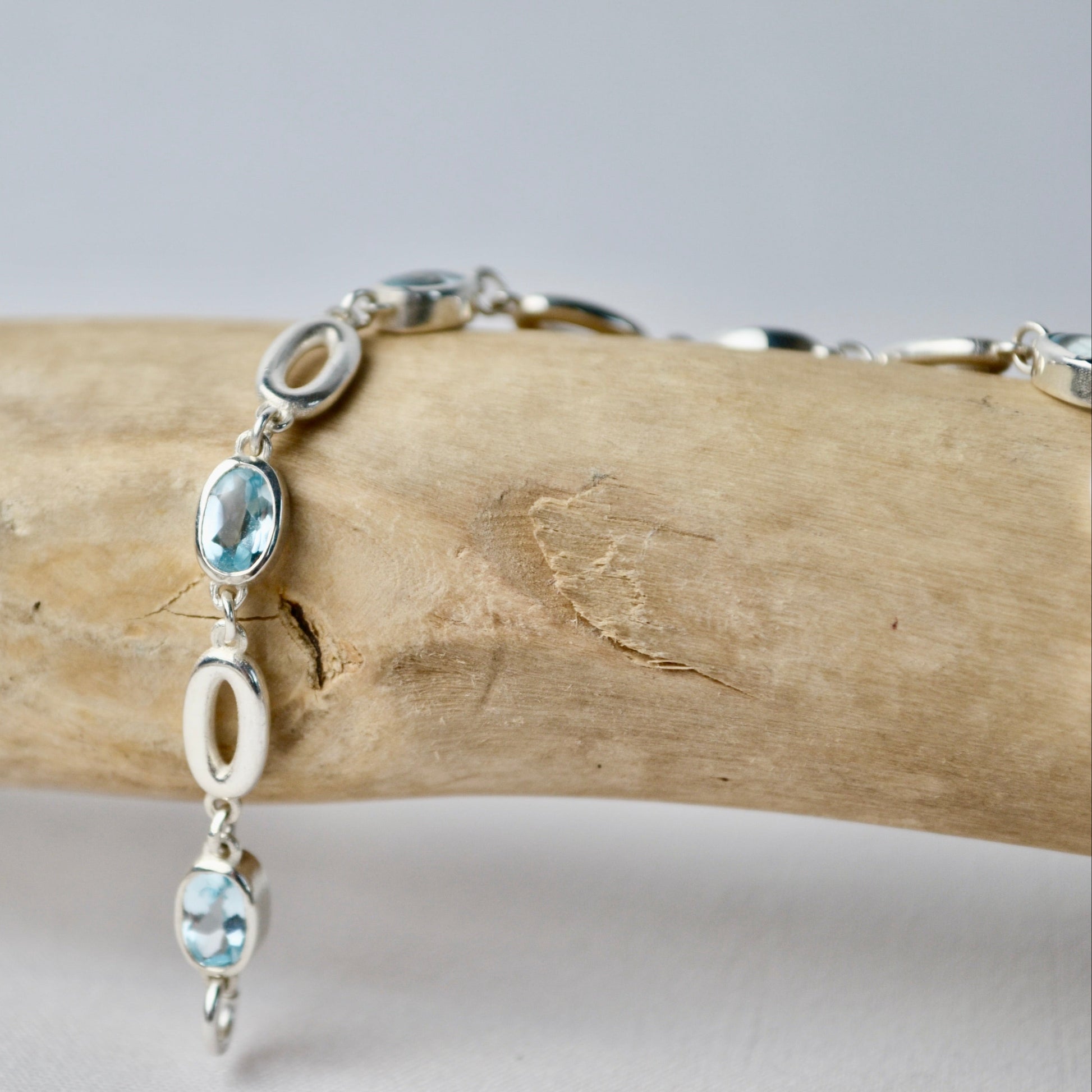Silver bracelet with blue gemstones on a wooden branch