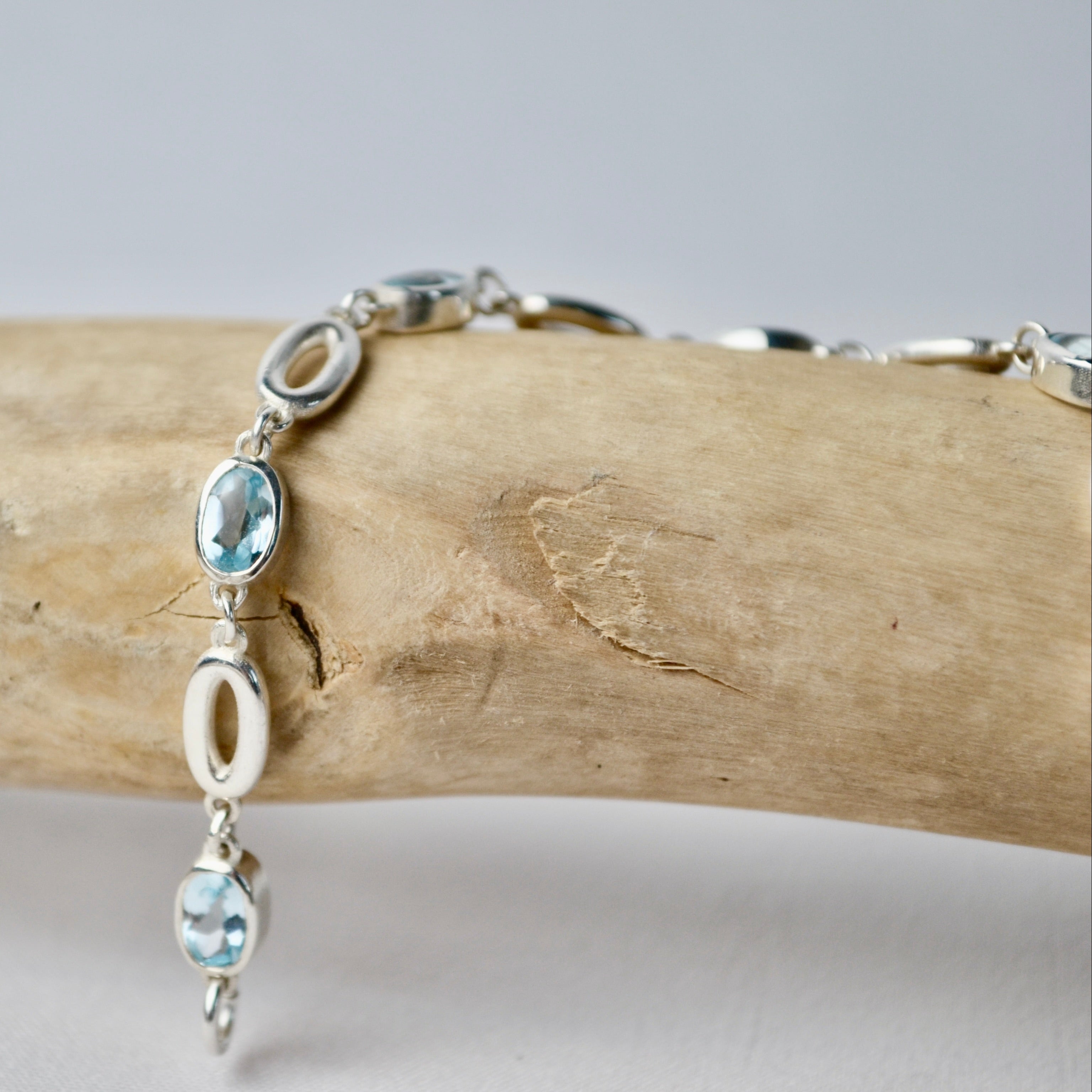 Silver bracelet with blue gemstones on a wooden branch