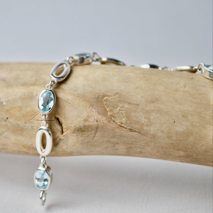 Silver bracelet with blue gemstones on a wooden branch