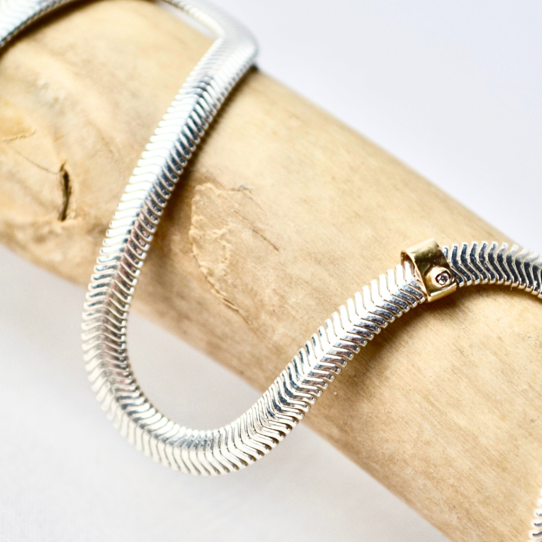 Silver snake chain bracelet on a wooden surface