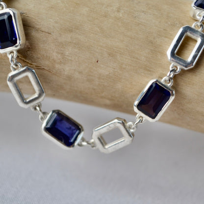 Silver bracelet with blue gemstones on a wooden surface