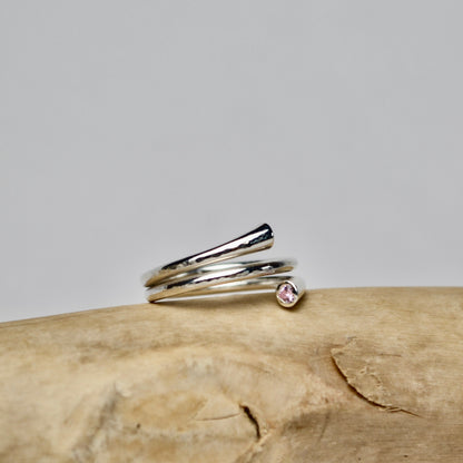 Silver ring with a small gemstone on a wooden surface
