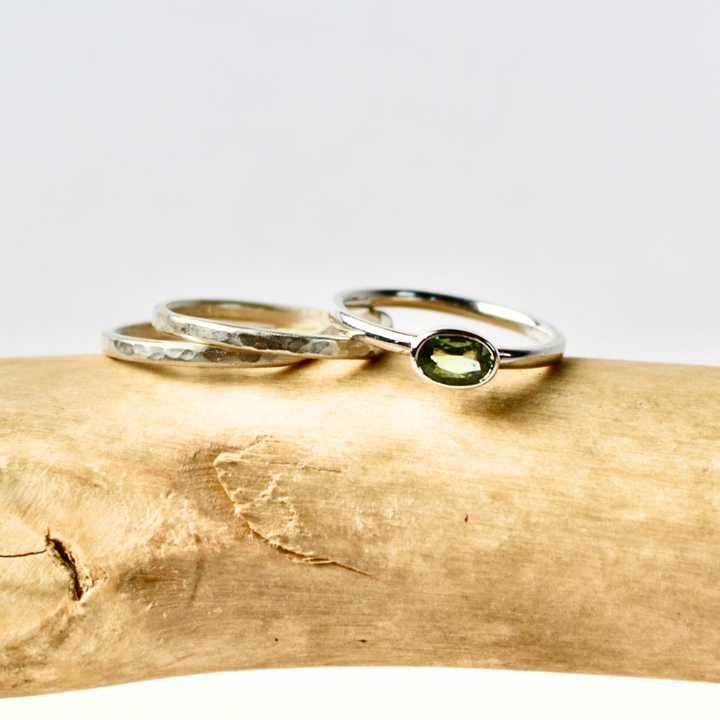 Two silver rings with green gemstones on a wooden surface