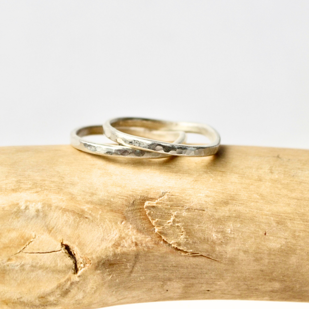 Two silver rings on a wooden surface with a white background