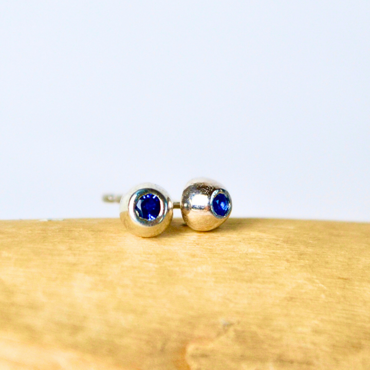 Silver earrings with blue gemstones on a wooden surface
