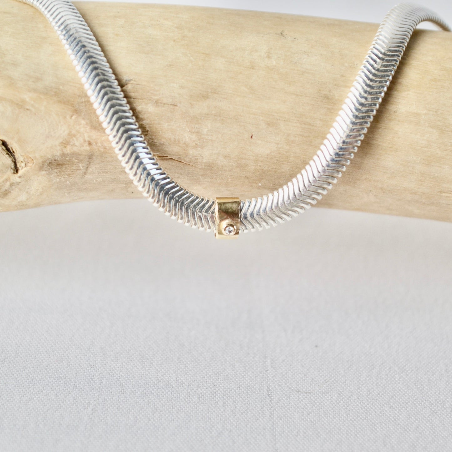 Silver snake chain necklace on a wooden surface