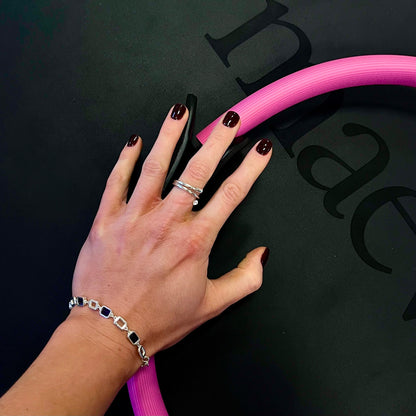 Hand with a pink tube against a black background with visible branding