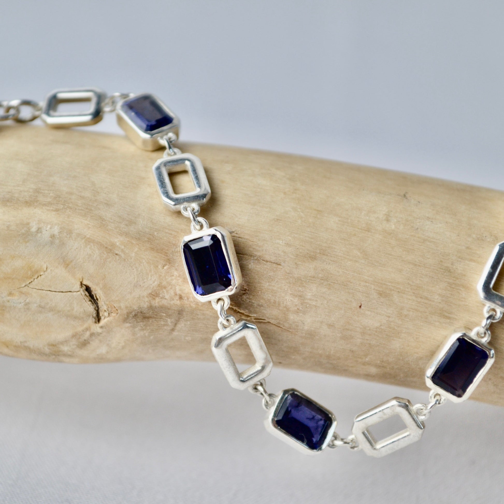 Silver bracelet with blue gemstones on a wooden stick
