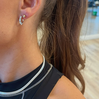 Close-up of a person wearing a diamond earring with a blurred background