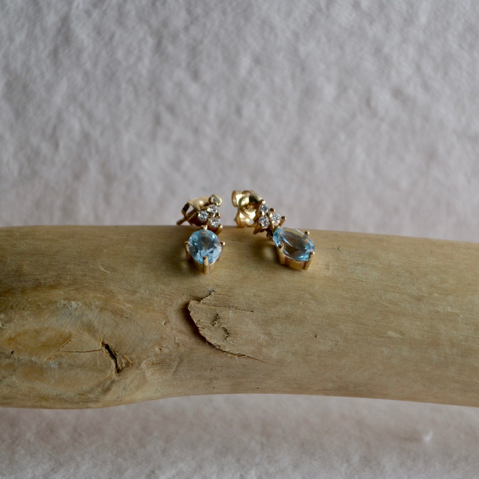 Gold earrings with gemstones on a wooden surface