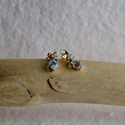 Gold earrings with gemstones on a wooden surface