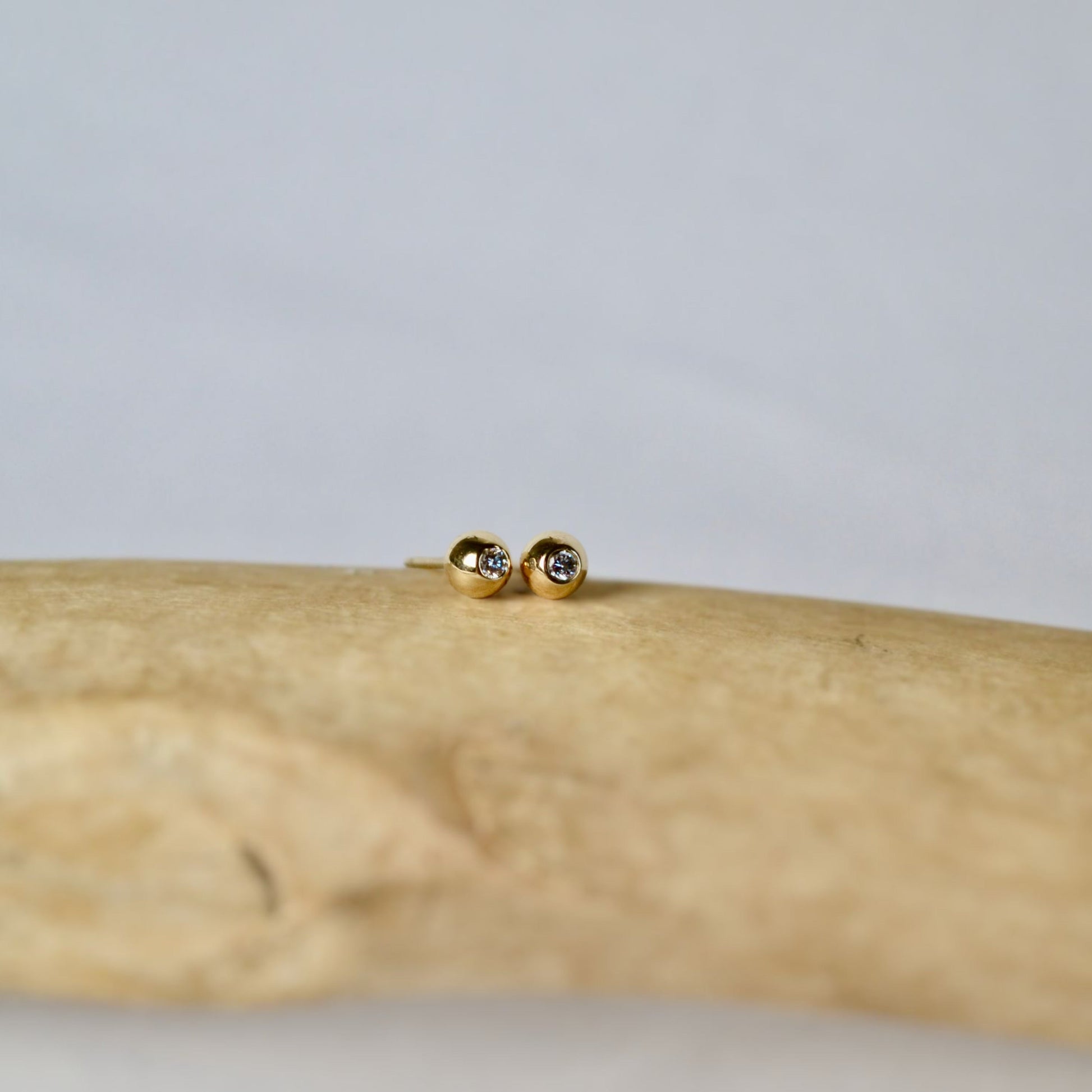 Gold earrings on a wooden surface with a neutral background