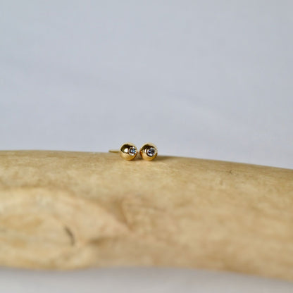 Gold earrings on a wooden surface with a neutral background
