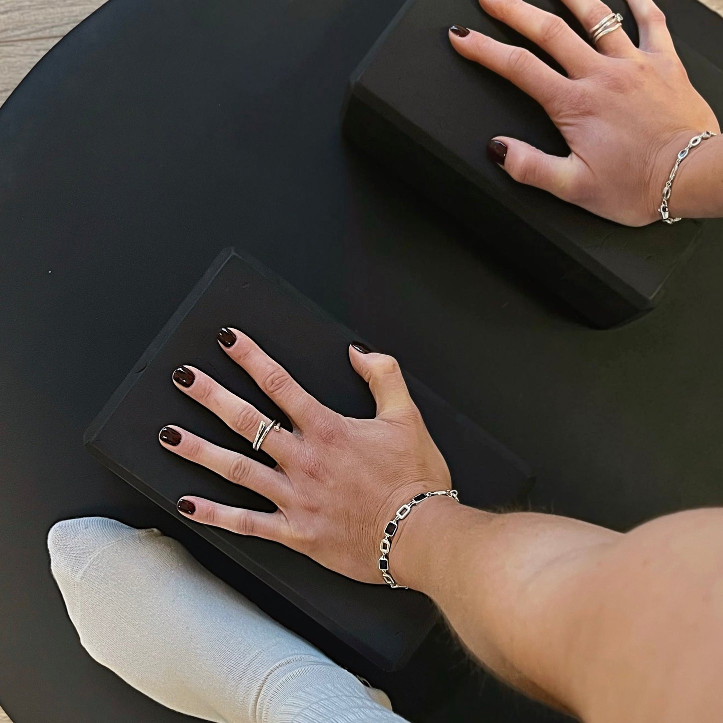 Close-up of hands with rings and bracelets on a black surface