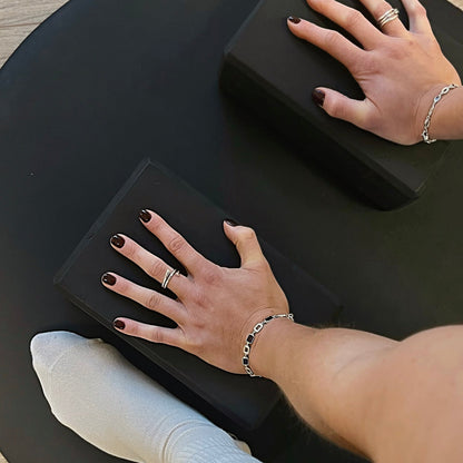 Close-up of hands with rings and bracelets on a black surface